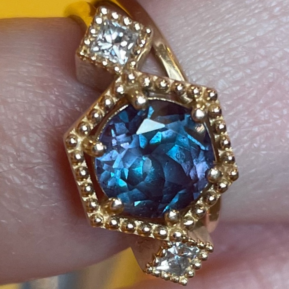 Lab alexandrite flanked by CZ in a 14k gold setting.